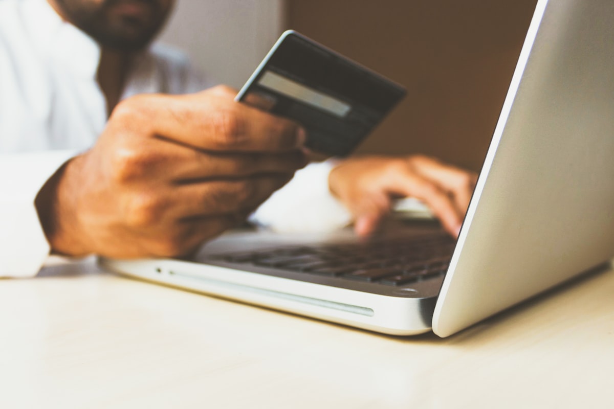 Person paying with a credit card next to a laptop — budgeting for mobile app development