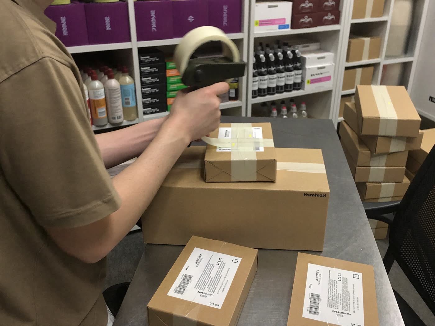 A person taping parcels at a packing bench